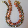 A beaded necklace made of alternating strands of faceted orange-brown agate and green moss agate beads, separated by small gold spacer beads, with a lobster clasp and gold chain extender on a light gray background.